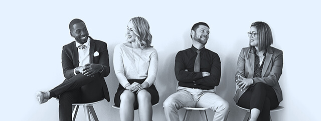 Four people sat on stools smiling