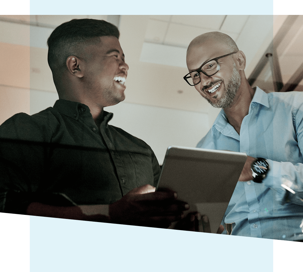 Two men smiling working on a laptop